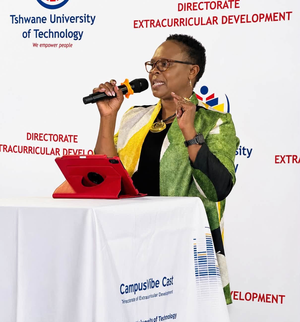 Prof. Rotich delivering a keynote at a university podium, holding a microphone