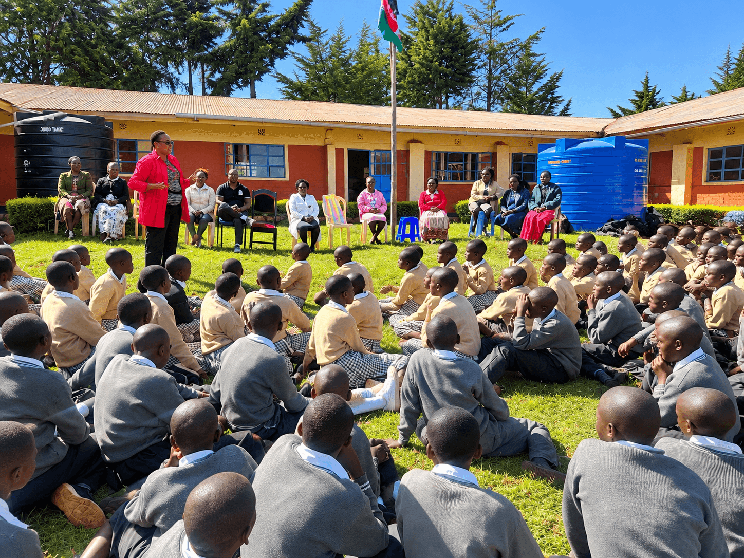 Prof. Rotich addressing students seated outdoors at a school in Kenya