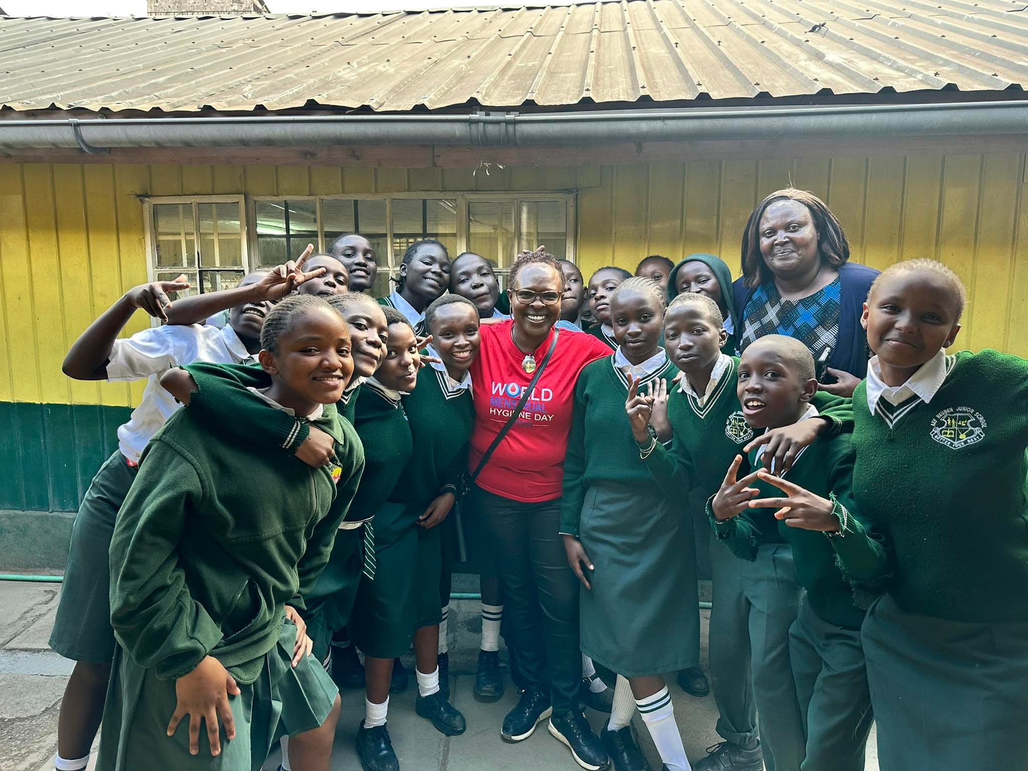 Prof. Rotich in a red WOYO shirt surrounded by smiling secondary-school students in green uniforms