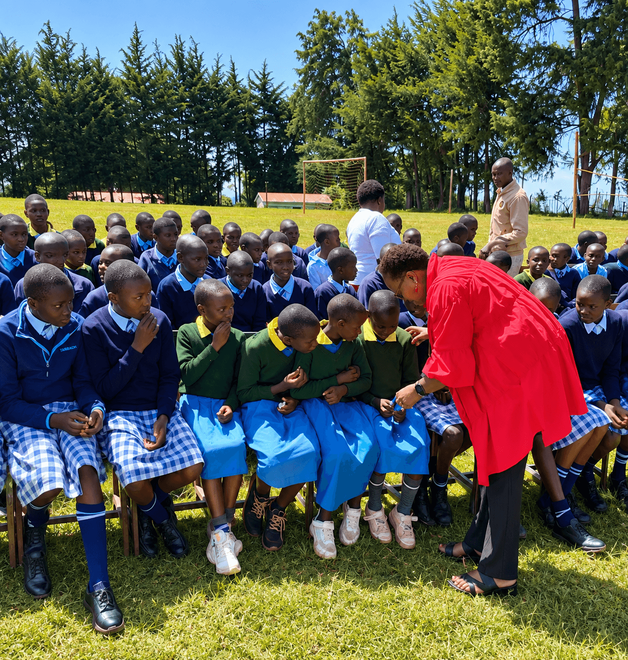 Prof. Rotich leaning in to speak with seated primary-school students